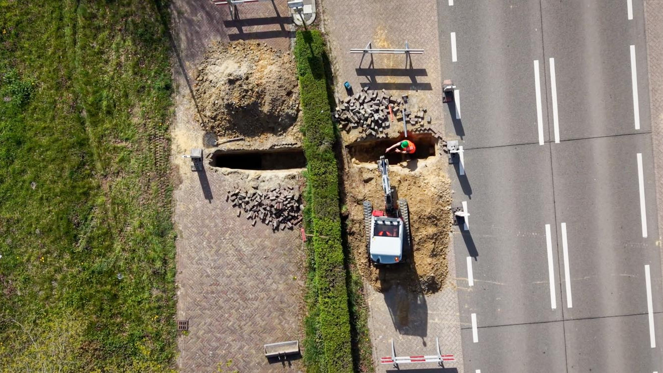 Luchtfoto van een sleuf voor rioleringswerk naast de weg