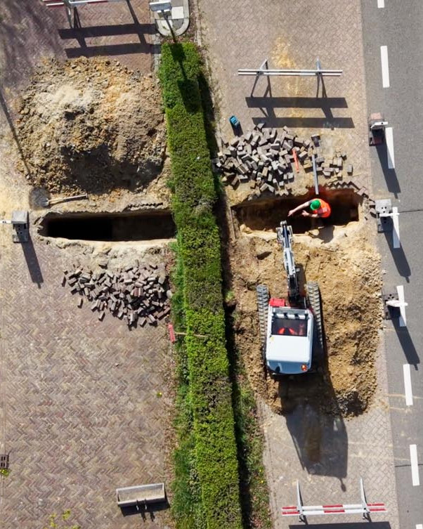 Luchtfoto van een sleuf voor rioleringswerk naast de weg